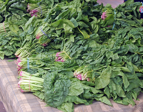 Bunches of spinach for sale at a farmers market.